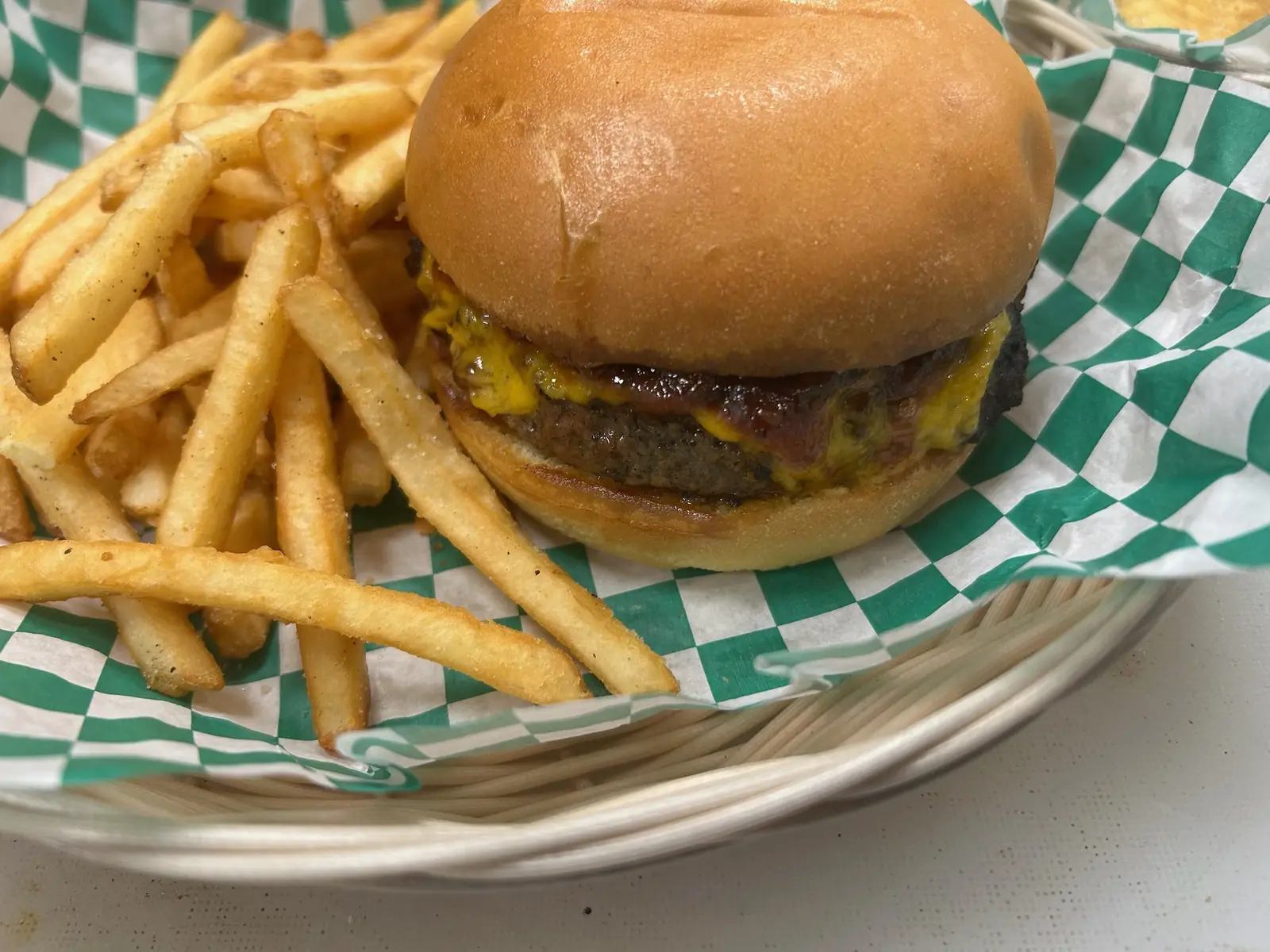A cheeseburger and fries served in a green-check basket at Tee Off at The Wharf